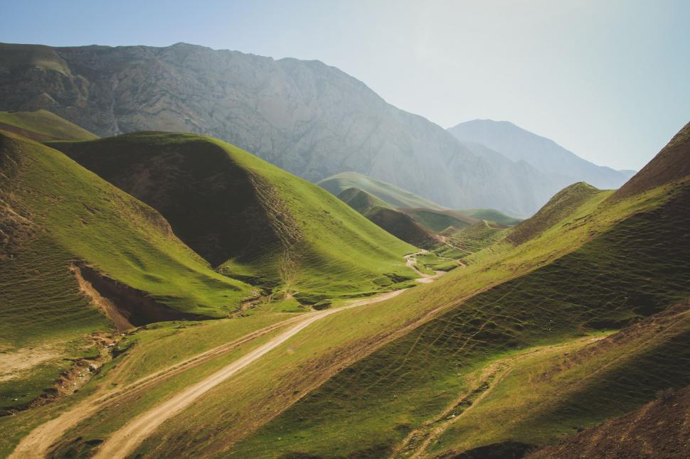 Free Image of Dirt Road Winding Through Lush Green Valley 