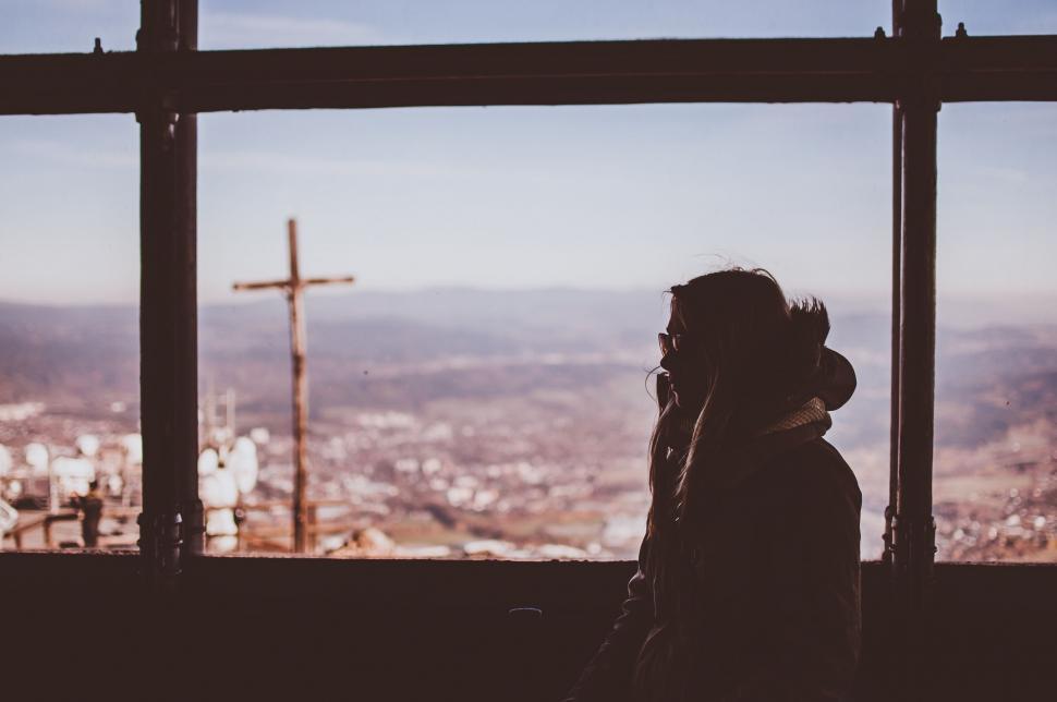 Free Image of Person Standing in Front of Window With Cross Background 