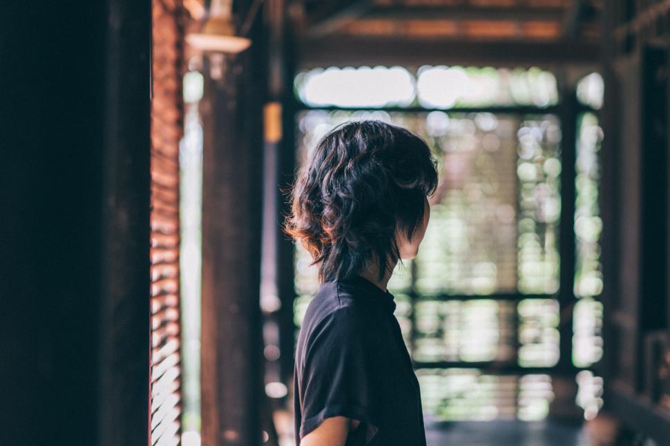 Free Image of Woman Standing in Building Looking Out the Window 