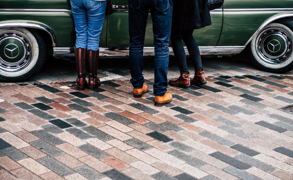 Free Image of Three People Standing in Front of a Green Car 