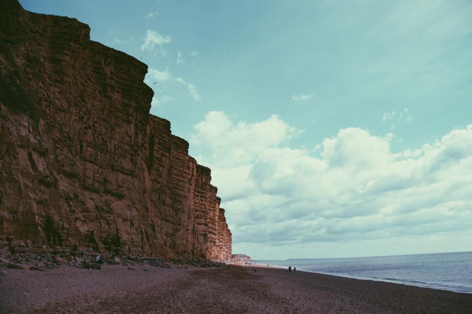 Free Image of Person Standing on Beach Next to Cliff 