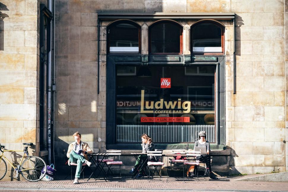 Free Image of Group of People Sitting on Bench in Front of Building 