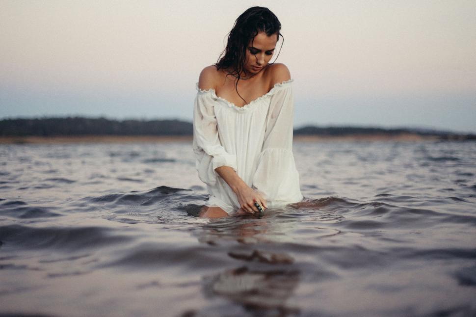 Free Image of Woman Standing in Water Wearing White Dress 