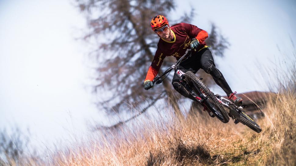 Free Image of Man Cycling Down Grass-Covered Hillside 