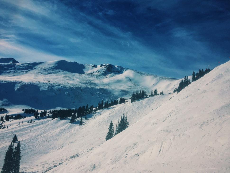 Free Image of Person Riding Snowboard Down Snow Covered Slope 