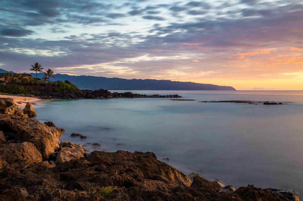 Free Image of Majestic Sunset Over Rocky Beach With Palm Trees 