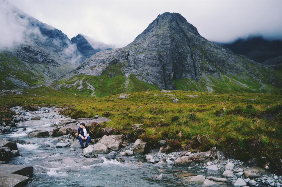 Free Image of Man Walking Across River Next to Mountain 