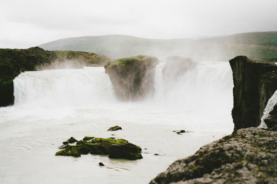 Free Image of Man Sitting on Rock Looking at Waterfall 