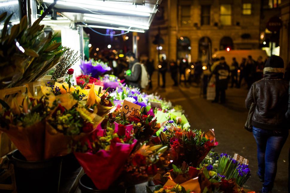 Free Image of Woman Walking Next to Bunch of Flowers 
