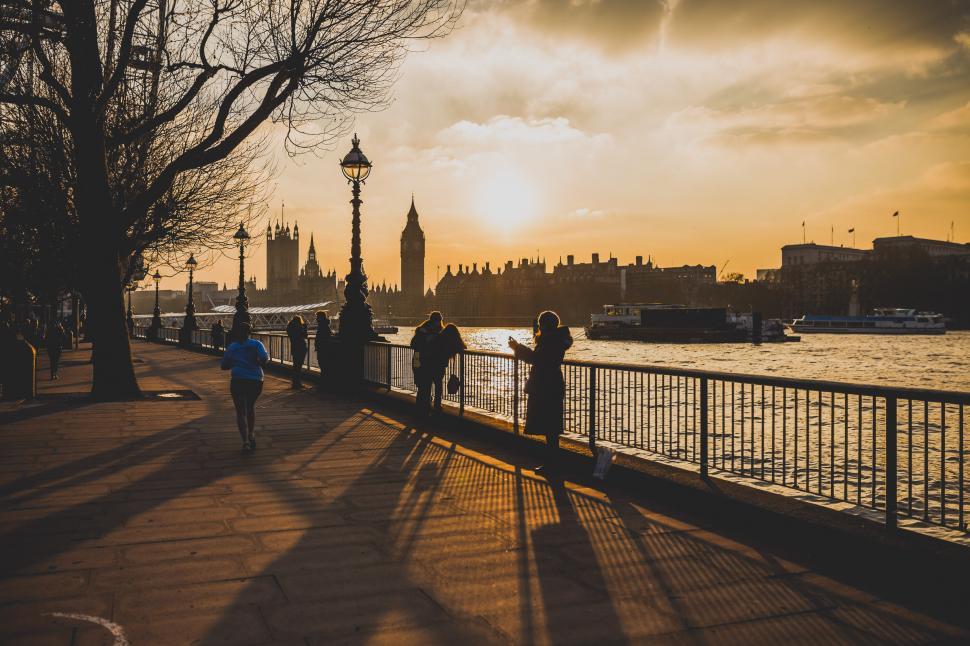 Free Image of Group of People Walking Down Sidewalk Next to River 