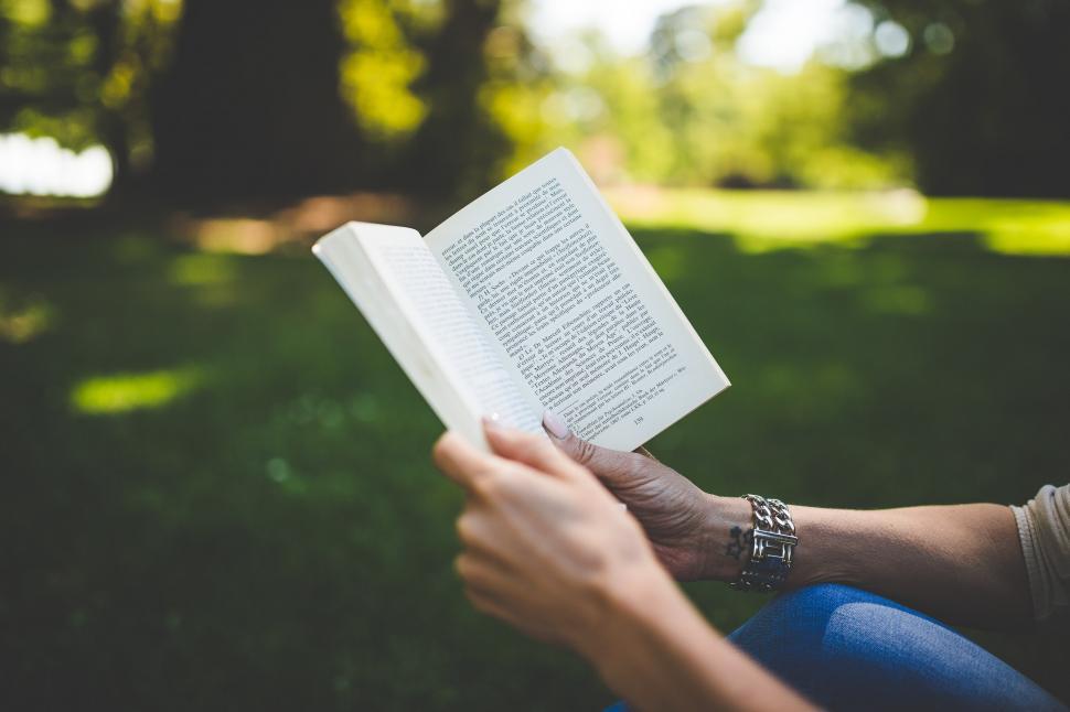 Free Image of Person Sitting in Grass Reading Book 