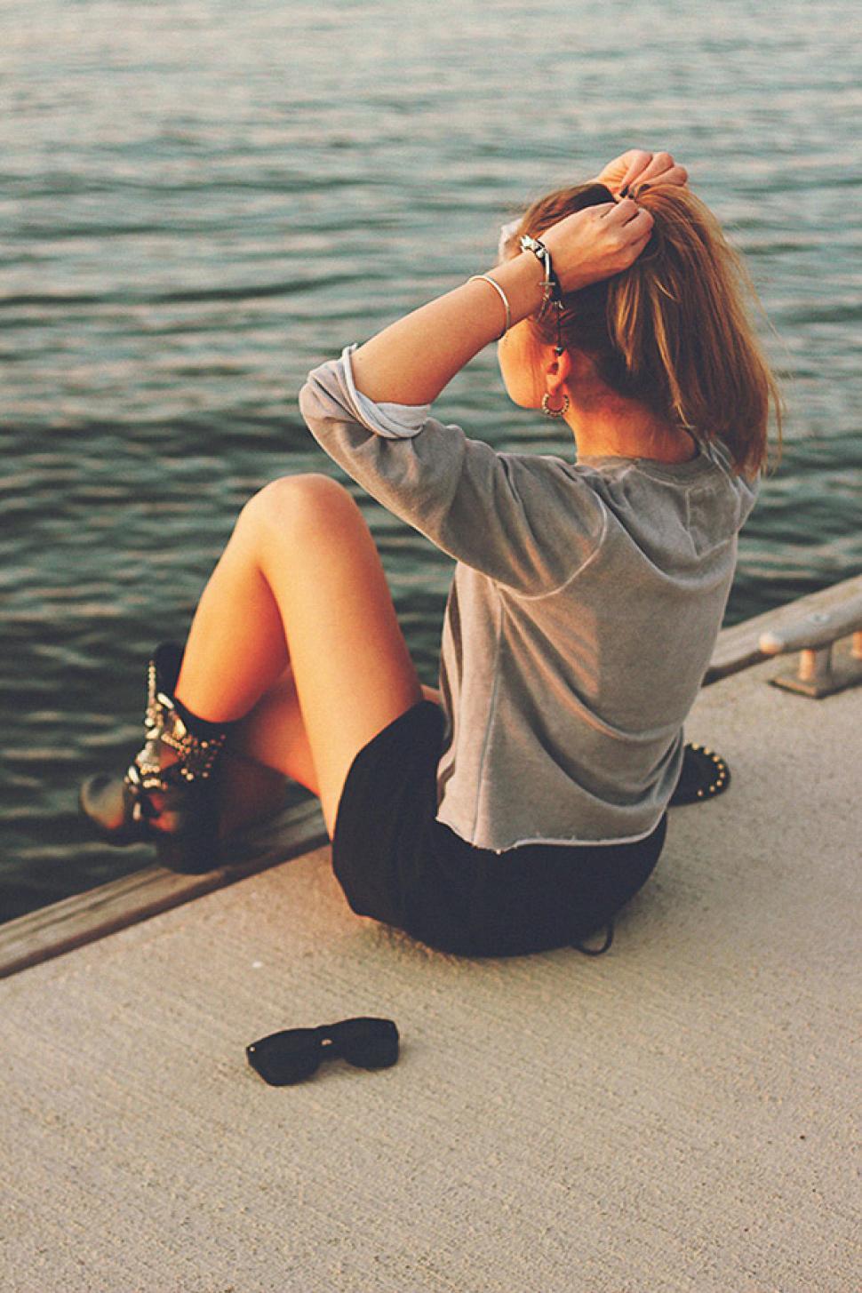 Free Image of Woman Sitting on Dock Looking at Water 