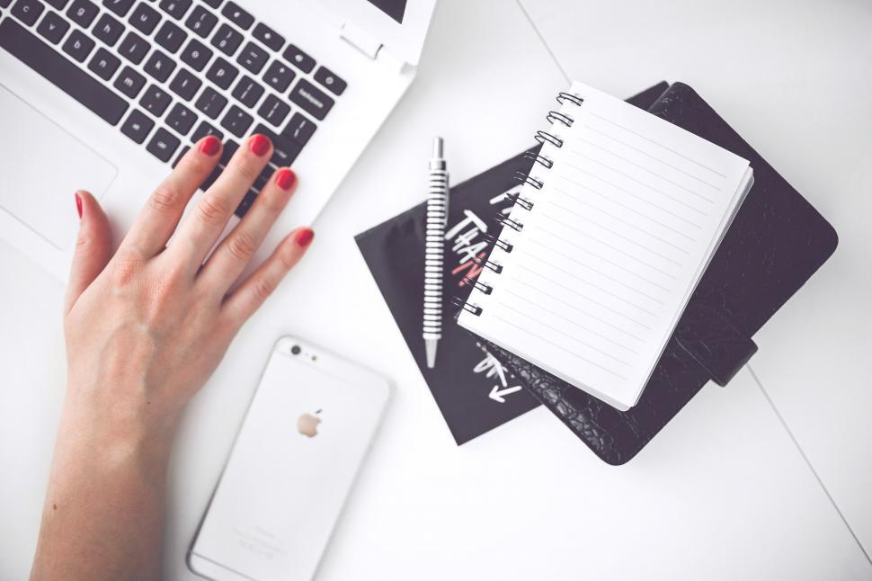 Free Image of Womans Hand Writing on Notebook Beside Laptop 