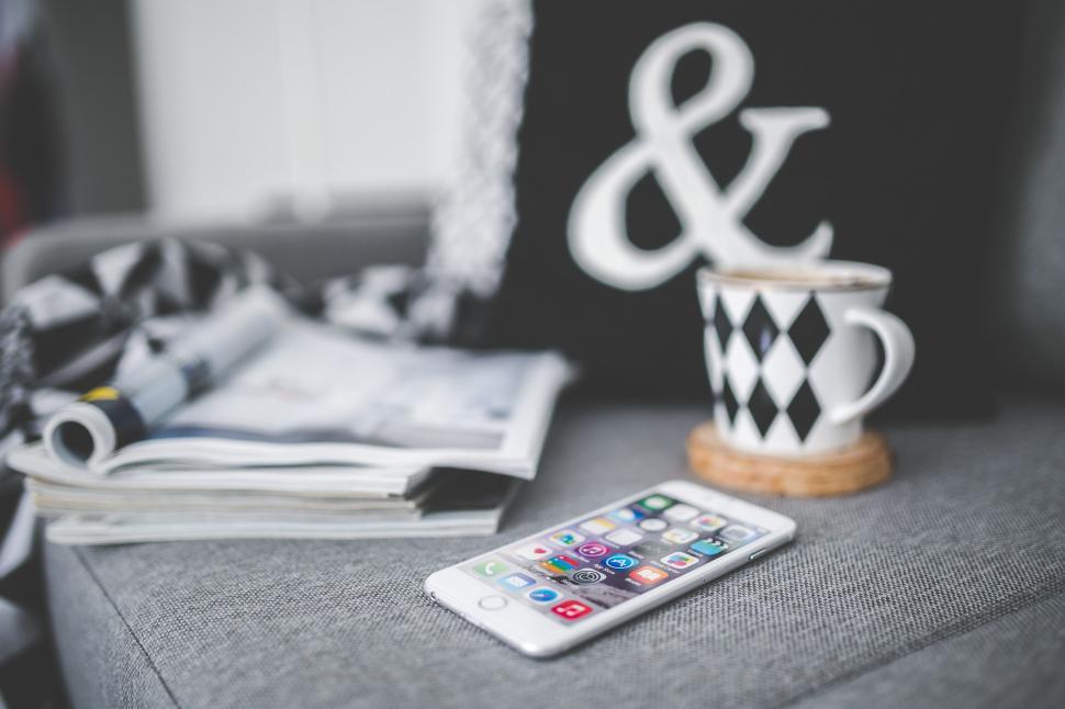 Free Image of Cell Phone on Couch Next to Cup 