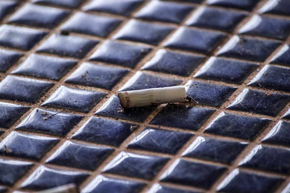 Free Stock Photo of Cigarette Resting on Tiled Floor