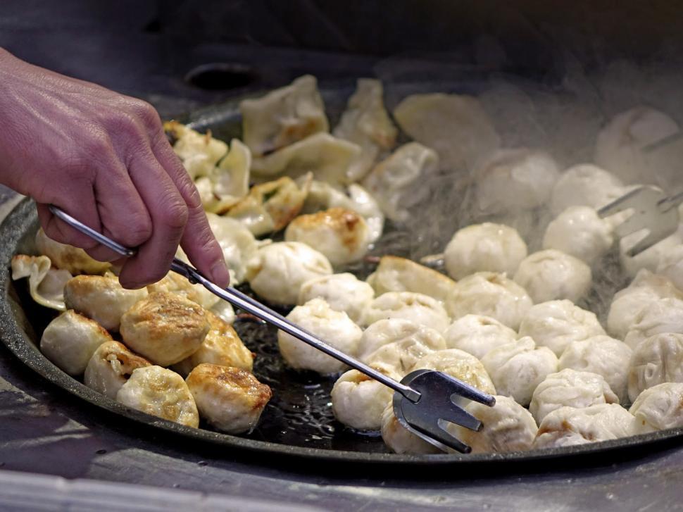 Free Image of Person Using Tongs to Fry Food in a Pan 