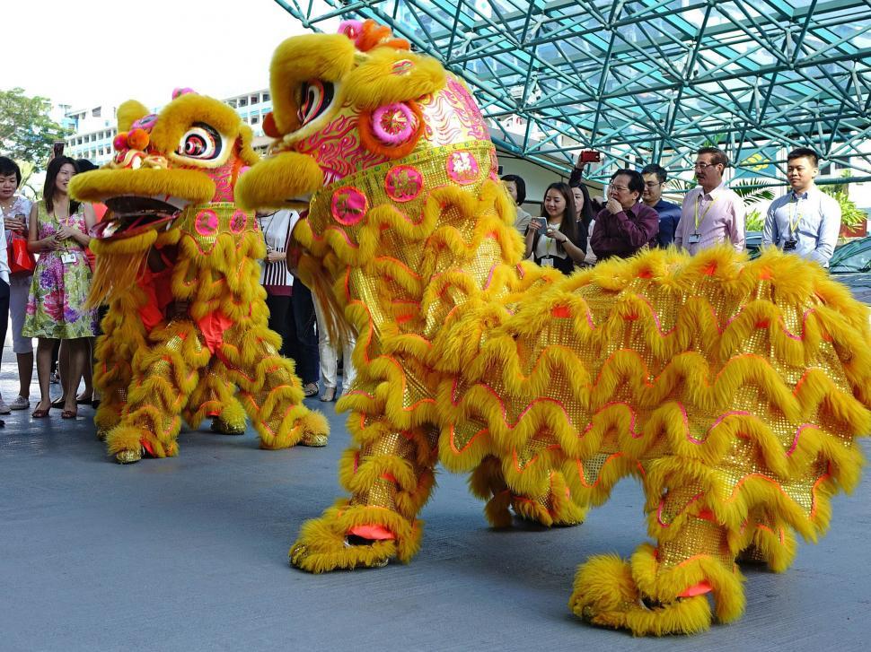 Free Image of Group of People Standing Around a Yellow Lion 