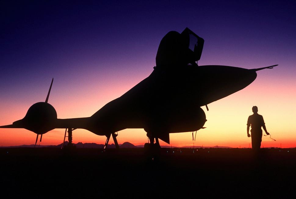 Free Image of Man Standing Next to Jet at Sunset 