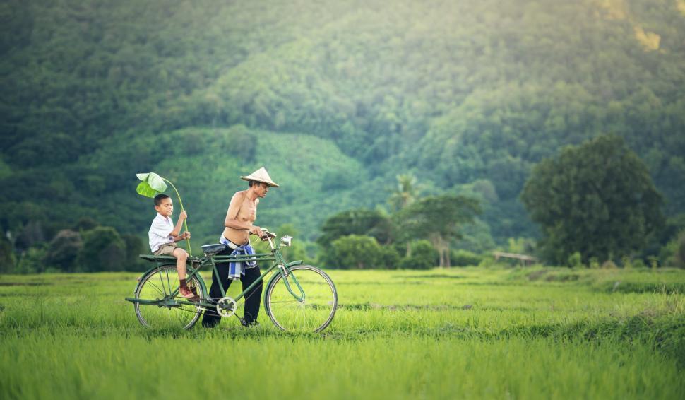 Free Image of Man Riding Bike With Boy on Back 
