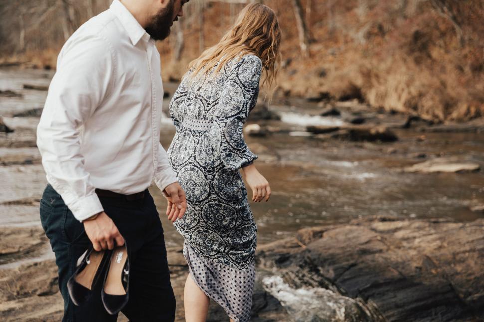 Free Image of A Man and a Woman Walking Along a River 
