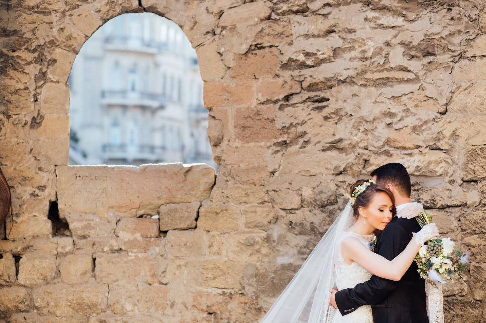 Free Image of Bride and Groom Standing in Front of Stone Wall 