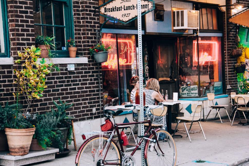 Free Image of Woman Sitting at Table Outside Restaurant 