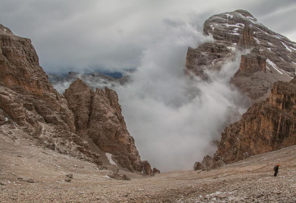 Free Image of Man Walking Up Mountain With Smoke Cloud 