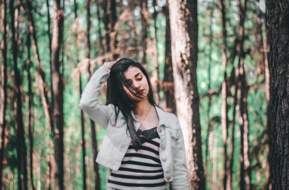 Free Image of Woman Standing in the Woods With Hand on Head 