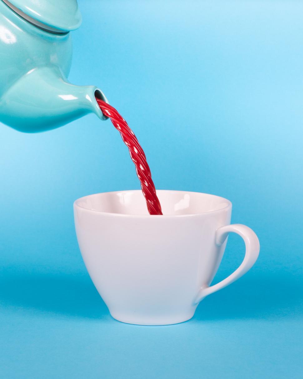 A person pouring Argentinian Red Bush Tea from a teapot into a delicate teacup.