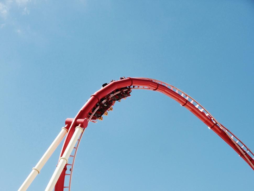 Free Image of Red and White Roller Coaster Against Blue Sky 