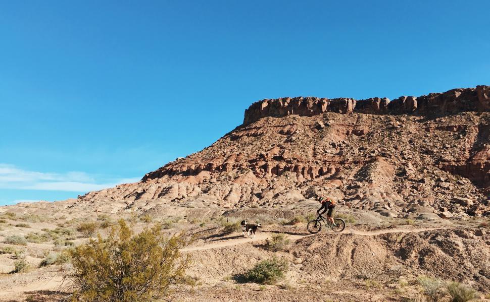 Free Image of Man Riding Bike Down Dirt Road 