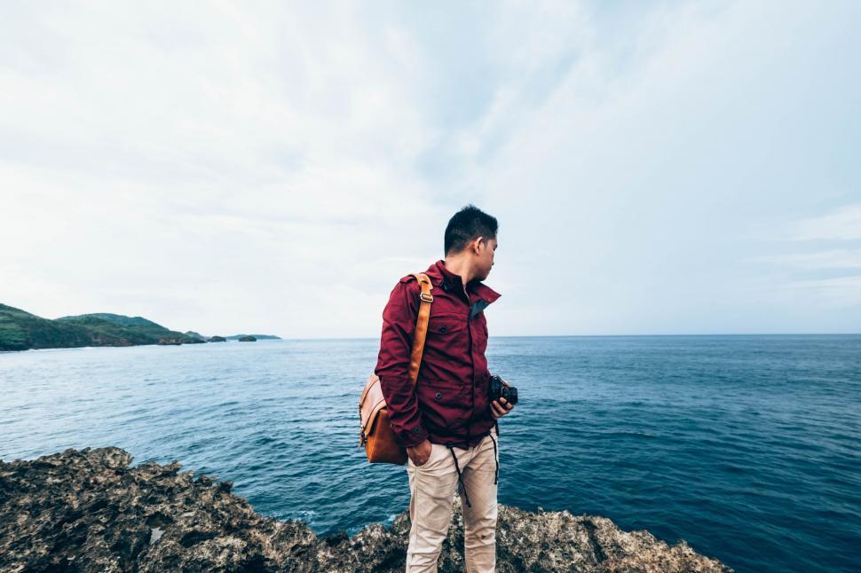 Free Image of Man Standing on Rocky Cliff by Ocean 