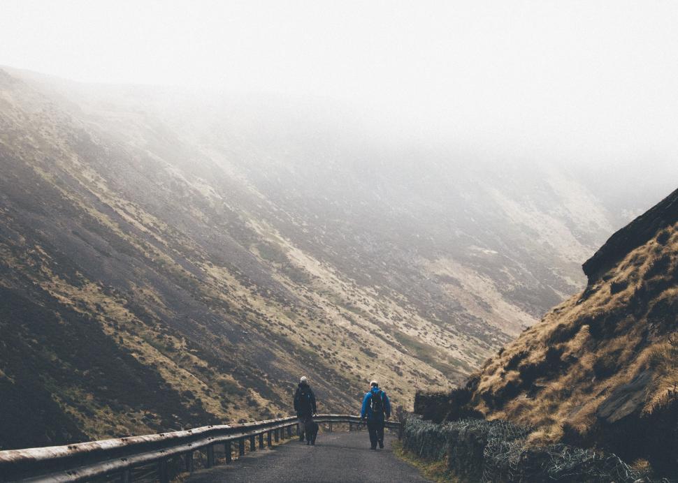 Free Image of Couple Walking Down Road Beside Mountain 