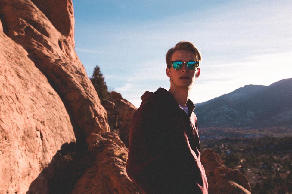 Free Image of Man Wearing Sunglasses Standing Next to Large Rock 