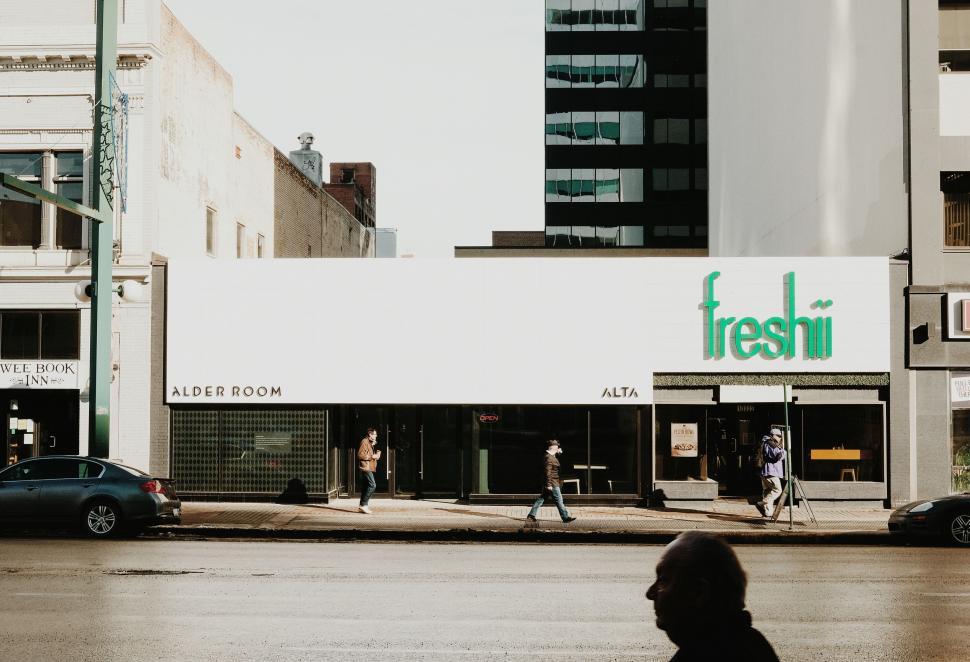 Free Image of Person Walking Across Street Next to Tall Buildings 