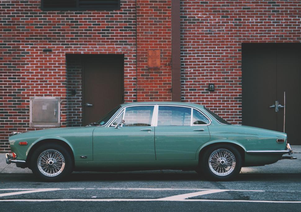 Free Image of Green Car Parked in Front of Brick Building 