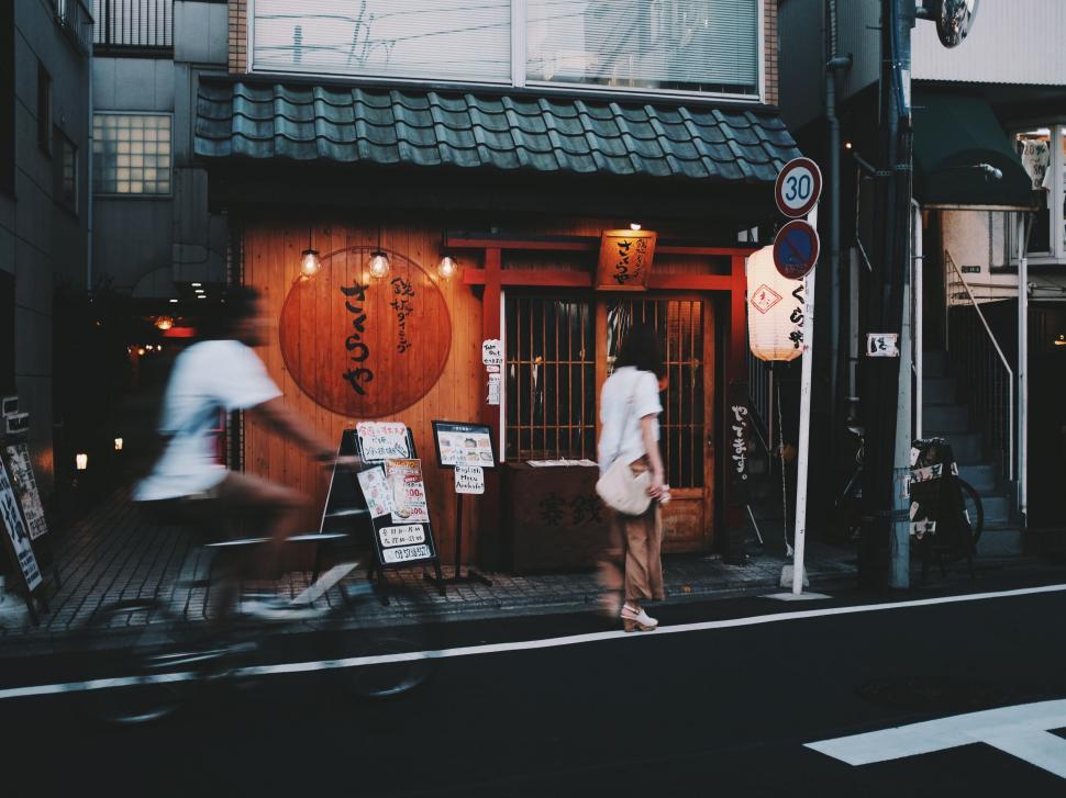 Free Image of Man Riding Bike Down Street Next to Tall Building 