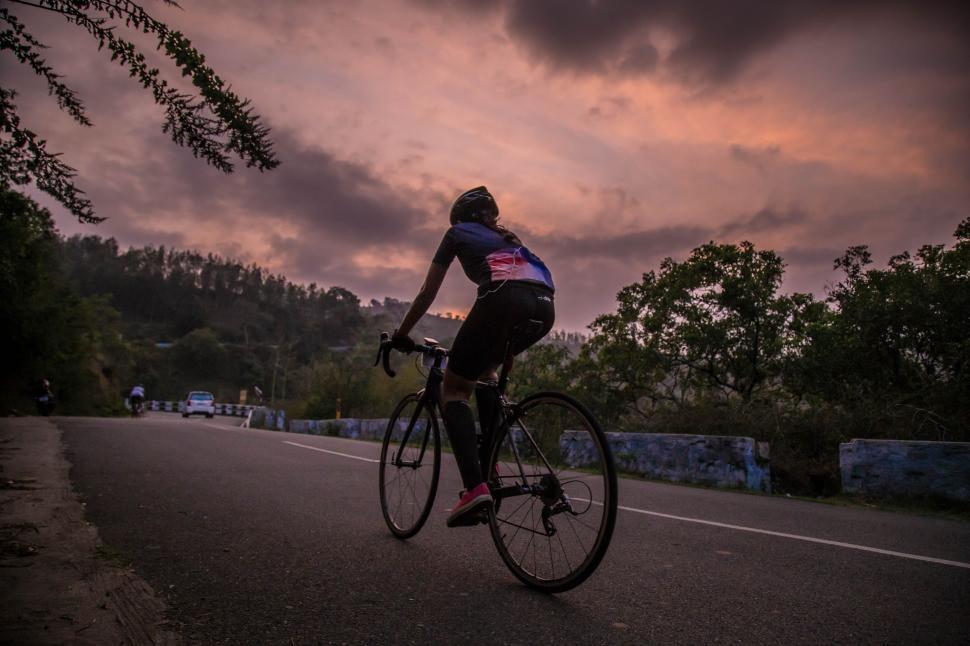 Free Image of Man Biking Down Street Under Cloudy Sky 