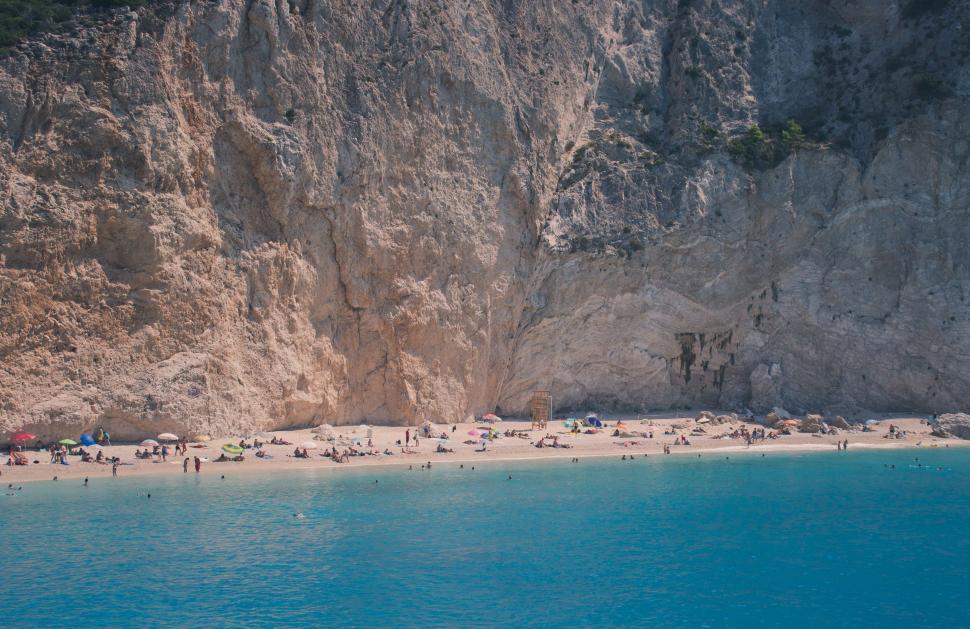 Free Image of Group of People Standing on Beach Next to Cliff 