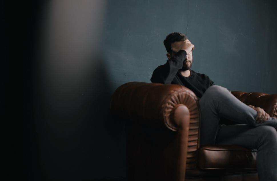 Free Image of Man Sitting on Couch Talking on Cell Phone 