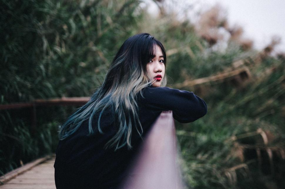 Free Image of Woman With Long Hair Standing on a Bridge 