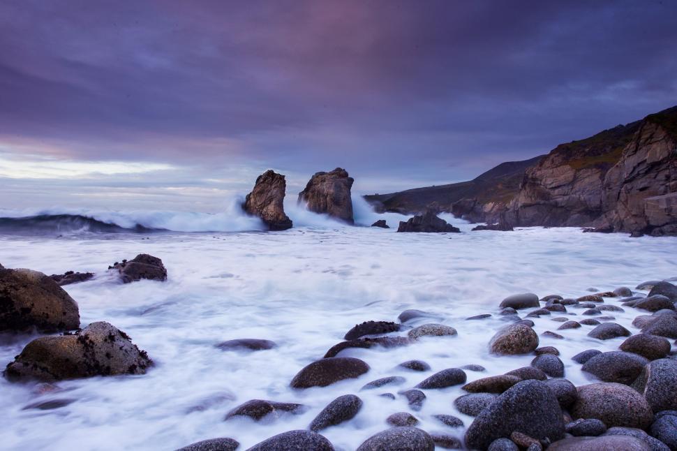 Free Image of Rocky Beach Covered in Rocks Under Cloudy Sky 