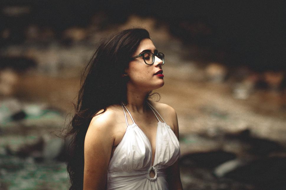 Free Image of Woman in a White Dress Looking Up at Something 