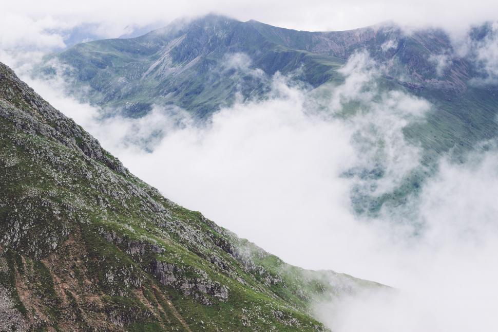 Free Image of Man Standing on Top of Mountain Next to Lush Green Hillside 