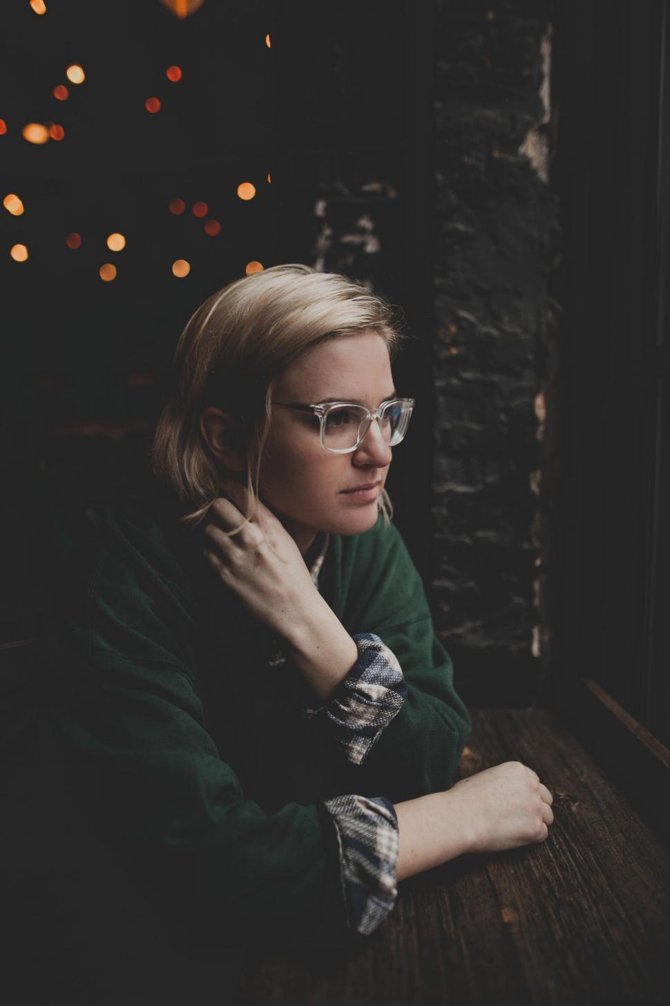 Free Image of Woman Wearing Glasses Sitting at a Table 