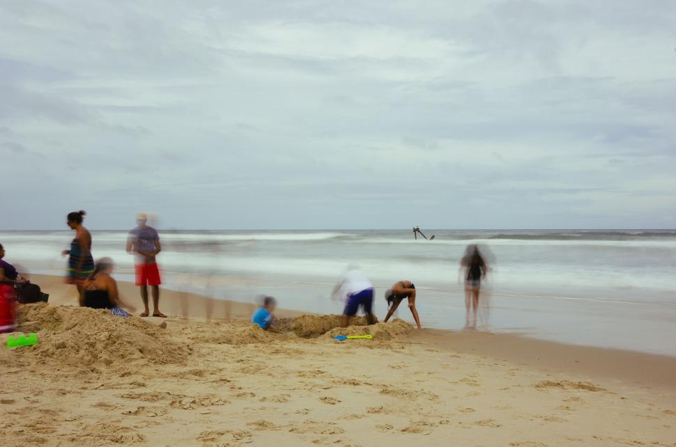 Free Image of Group of People Standing on Top of Sandy Beach 