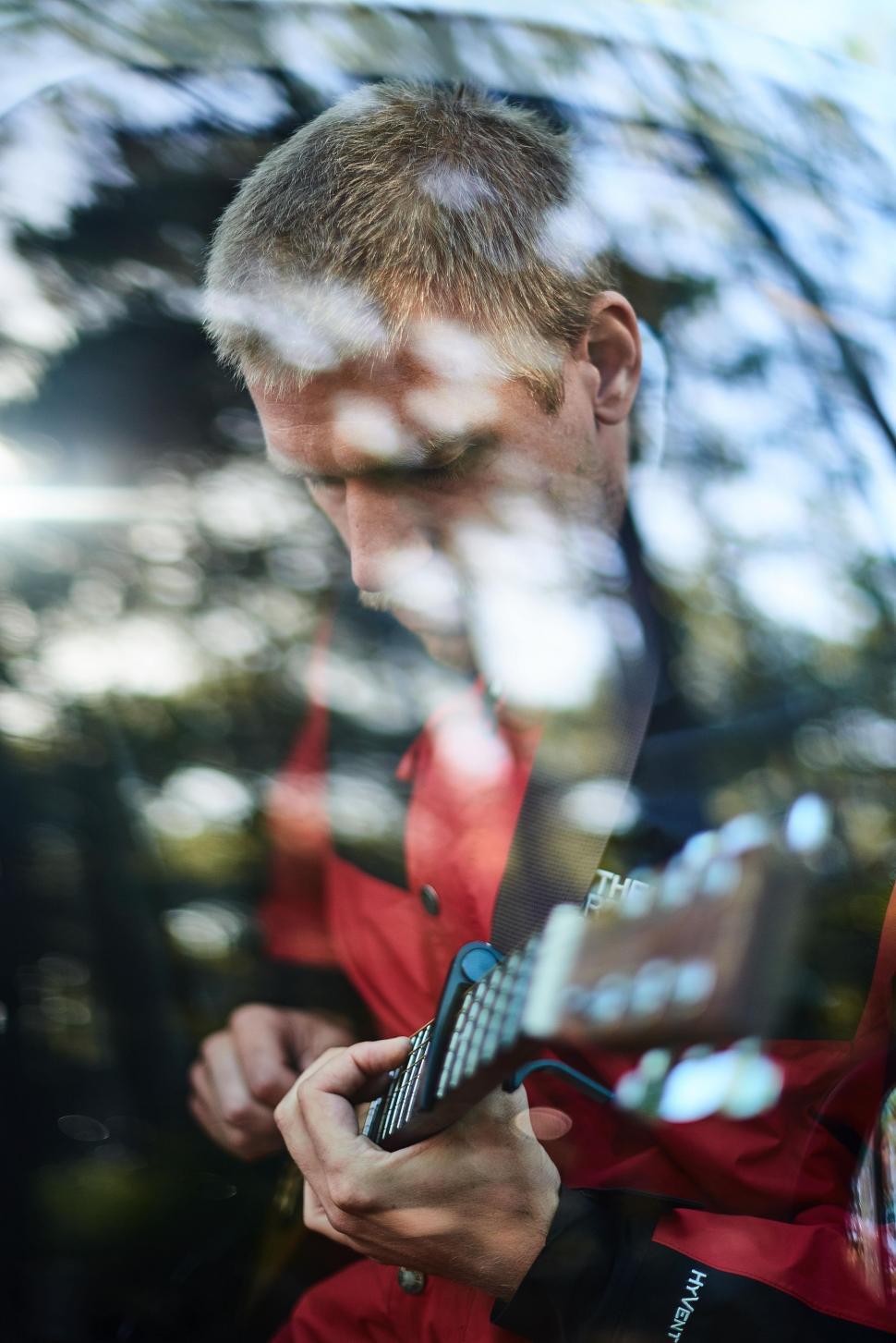Free Image of Man in Red Jacket Looking at Cell Phone 