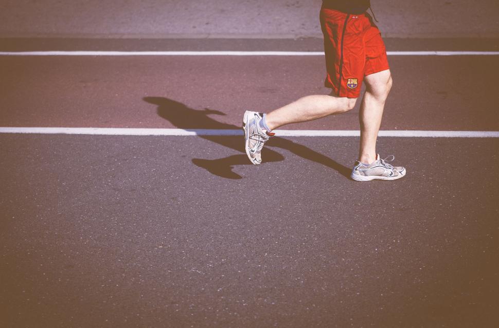 Free Image of Man Running on Street in Red Shorts and Black Shirt 