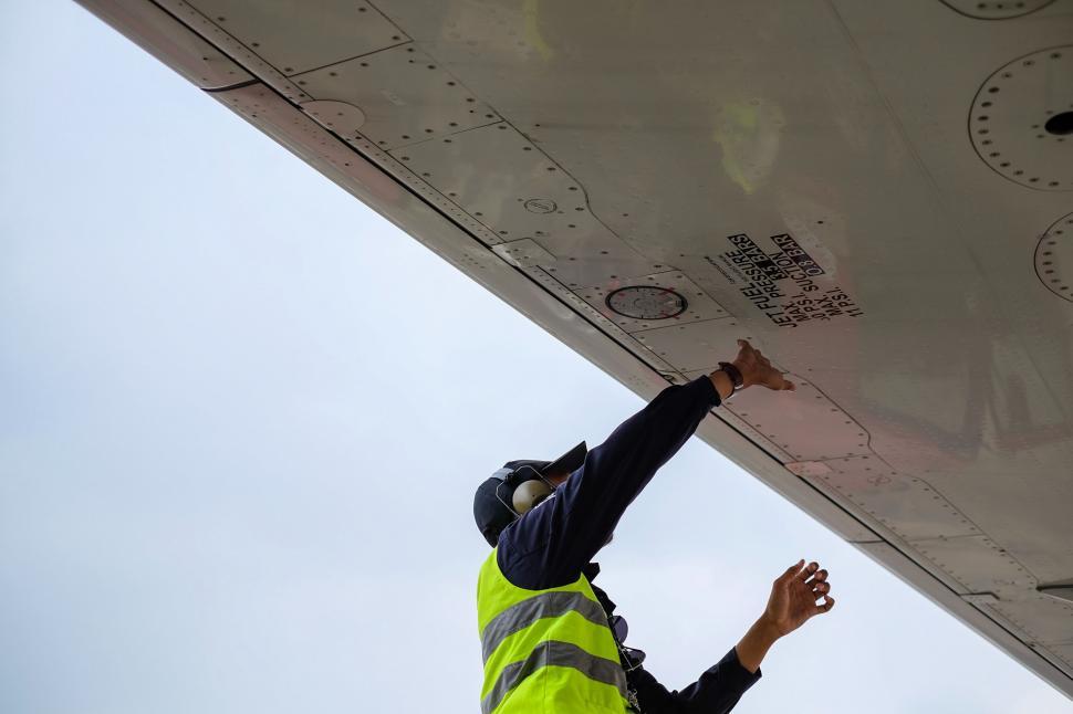 Free Image of Man in Yellow Safety Vest Standing Next to Airplane 