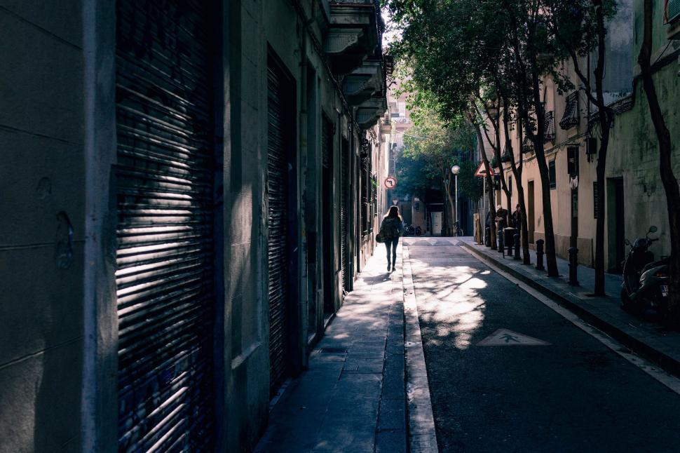 Free Image of Person Walking Down Urban Street Along Tall Buildings 